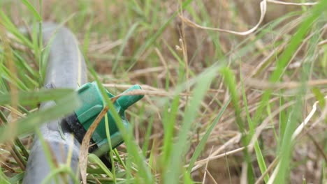 Close-Up-View-Of-Drip-Irrigation-Outlet-On-Ground-Surrounded-By-Grass-Blades