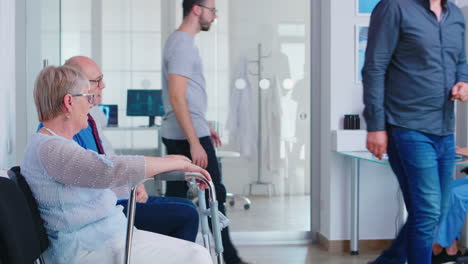 disabled senior woman talking with old man in hospital waiting room