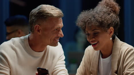 smiling coworkers looking at cellphone screen