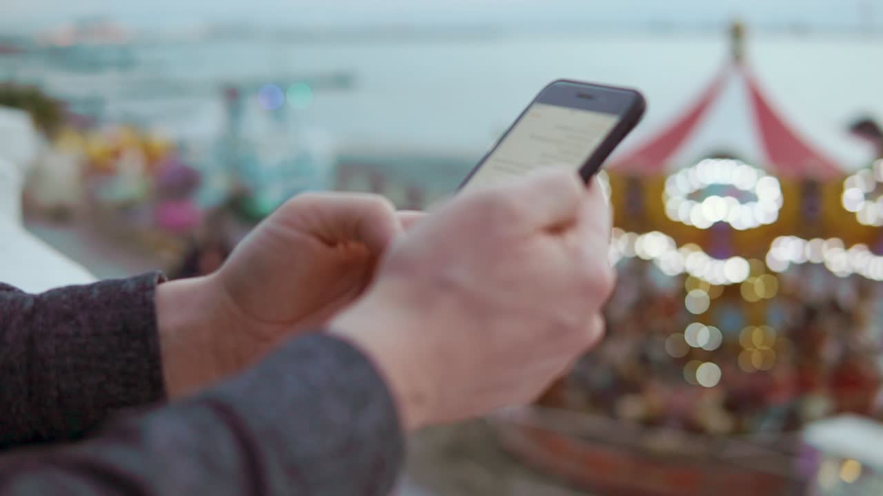 persona que utiliza un teléfono inteligente en un parque de atracciones
