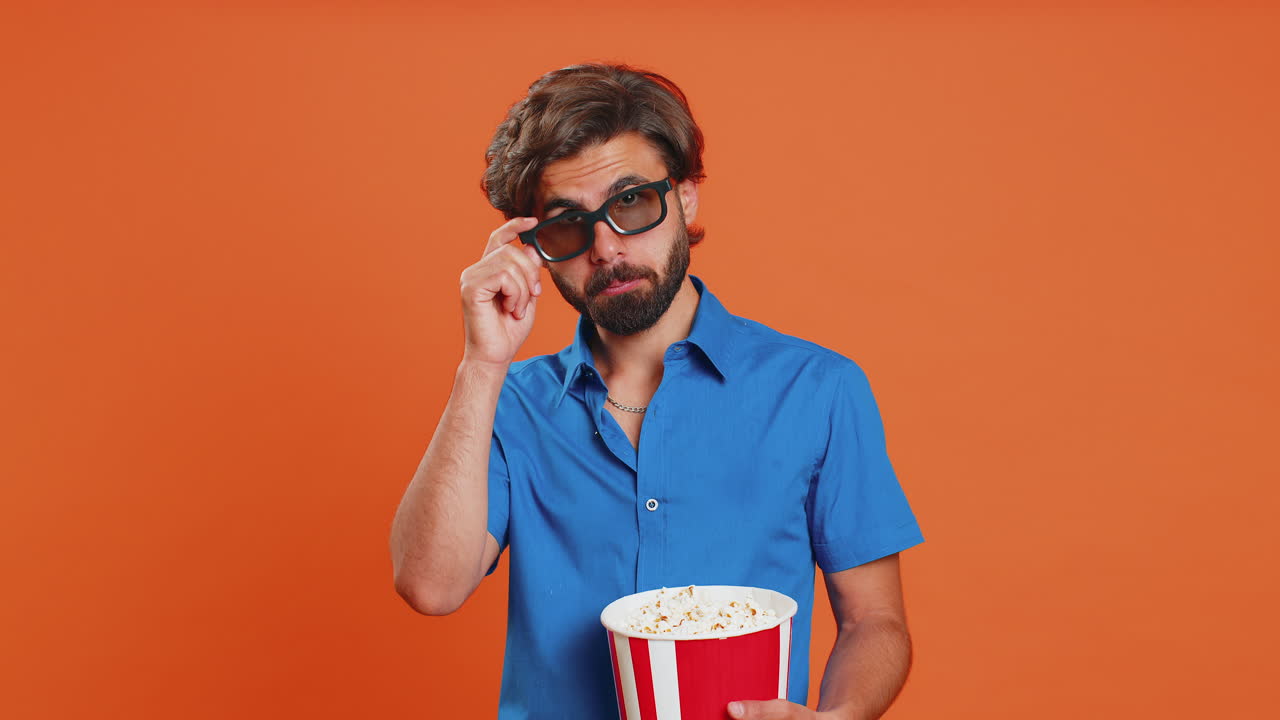 Man in 3D glasses eating popcorn and watching interesting tv serial, sport game film, online movie