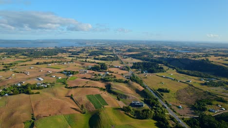 aerial wide view of lemuy island, countryside scenery with green fields sprawling to the sea, chile