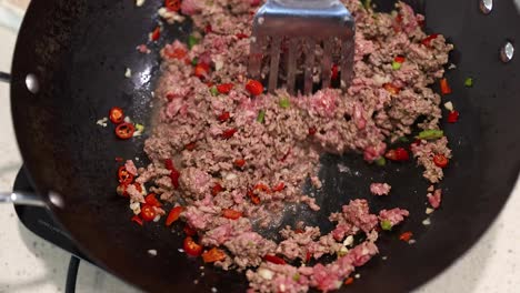 ground beef and vegetables are stir-fried in a wok, showcasing a vibrant cooking process with a spatula
