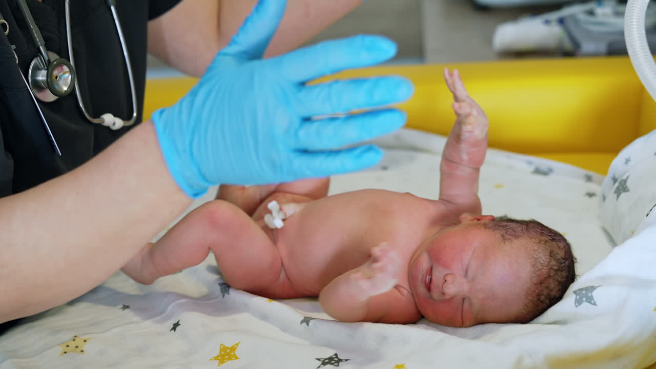 Naked newborn baby screams while the doctor examining him. Neonatologist's check up in the maternal hospital.