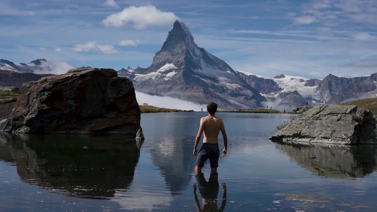 una foto de un hombre nadando frente a la montaña matterhorn en suiza, nadando en un lago helado