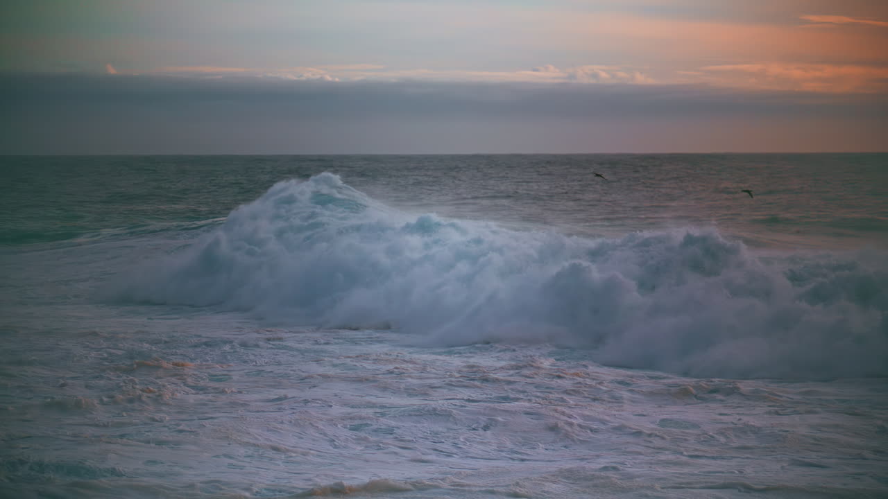 огромные морские волны пенят на утреннем горизонте. мощные волны качаются, ломая мелководье.