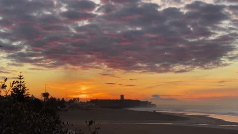 vista aérea sobre el tractor en funcionamiento en la playa de carcavelos, amanecer en portugal