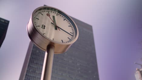 london canary wharf clock in front of a big skyscraper building during daytime as the seconds and minute pass in a sunny day