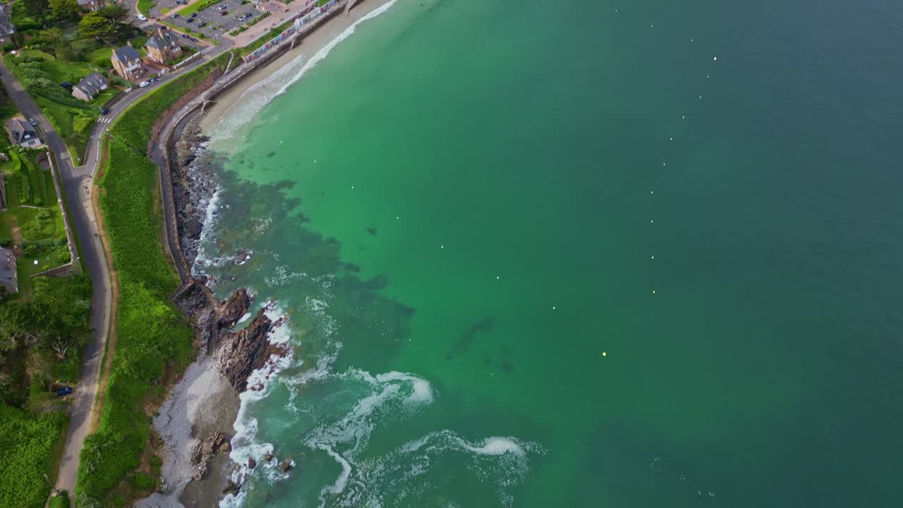 Vertically tilted up drone movement at Pointe du Chateau endpoint to the Perros-Guirec coastal settlement with curving Trestrignel beach, Brittany, France.
