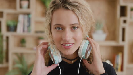 portrait of beautiful young blonde woman listening to music removes headphones smiling enjoying leisure activity entertainment