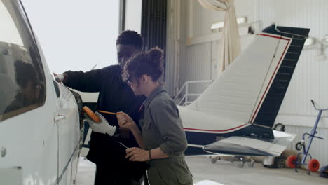 two technicians using multimeter and taking notes during hangar repair work