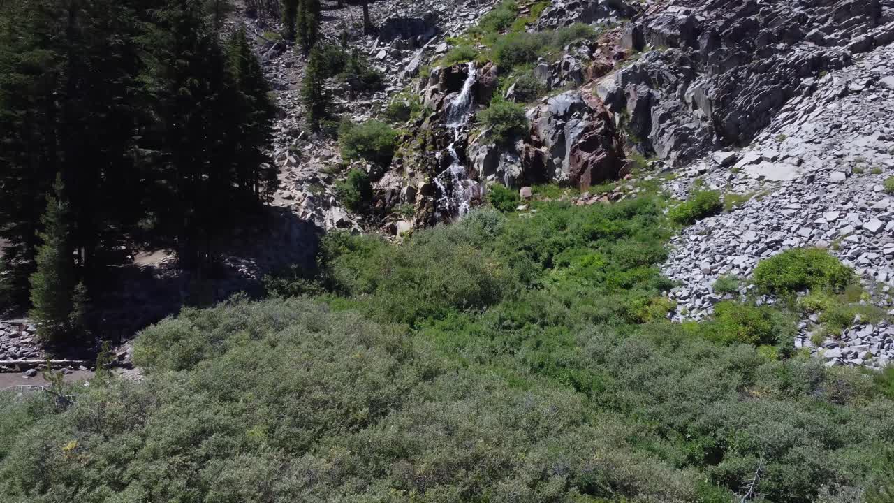 zoom toma aérea de una cascada alpina mientras camina un excursionista