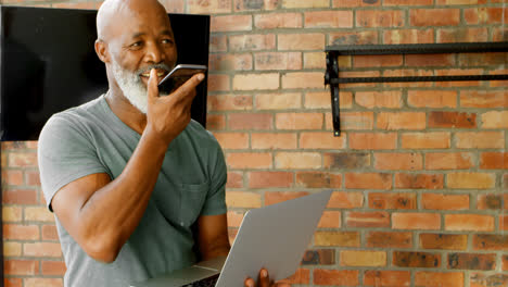 Senior-man-talking-on-mobile-phone-while-using-laptop-4k