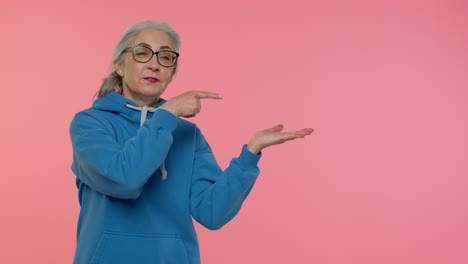 abuela madura mostrando los pulgares hacia arriba y señalando un lugar vacío, área de publicidad para texto comercial