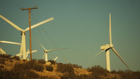 Steady-close-up-of-rotors-and-blades-of-wind-turbines-at-a-wind-farm-with-hill-in-the-foreground-near-Palm-Springs-in-the-Mojave-Desert,-California,-USA