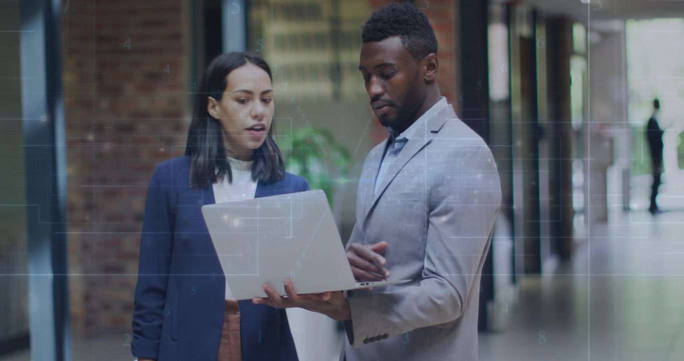 Man opening laptop, woman flipping binder reviewing business plan in hall, charts overlaying screen