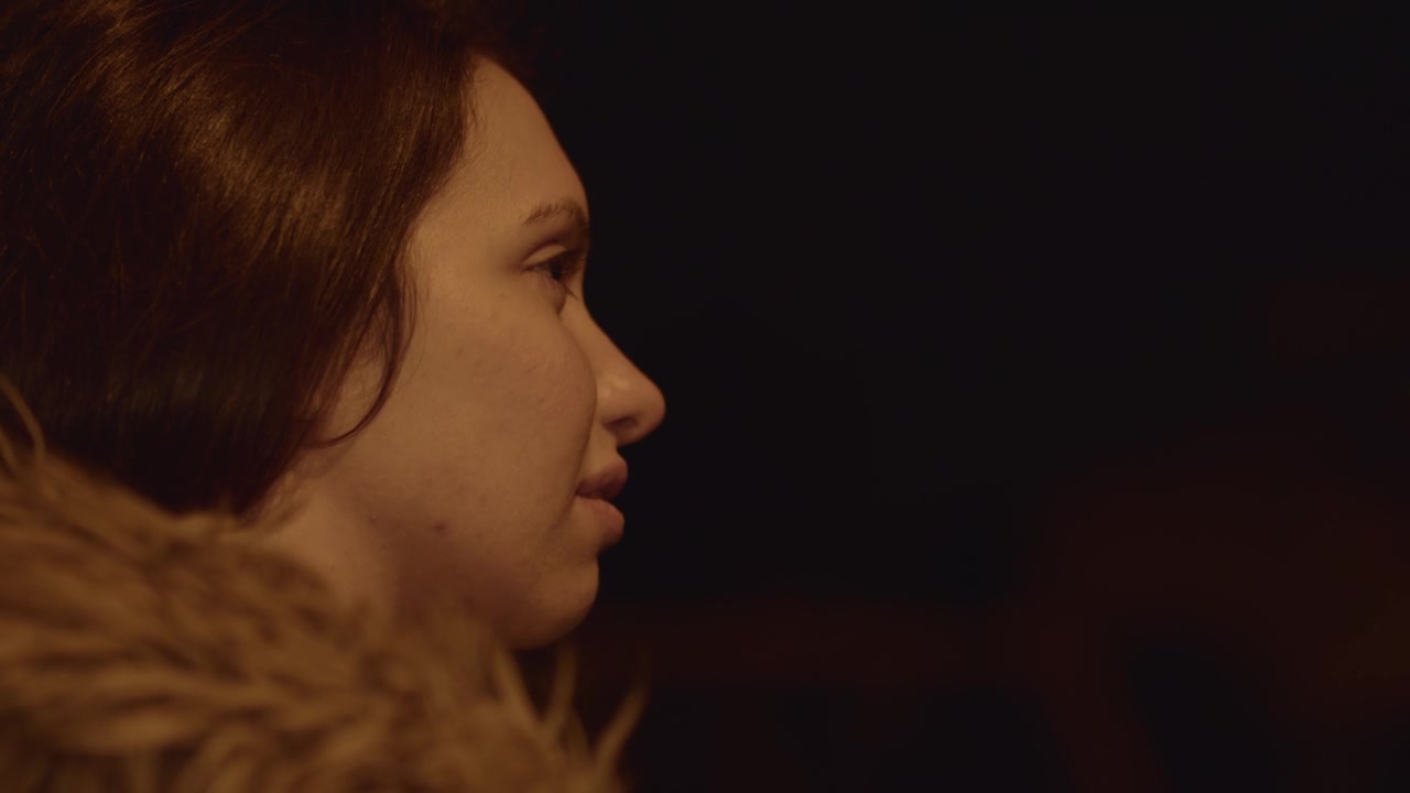 Profile of a young North European Caucasian woman with a serious gesture in front of a black background.