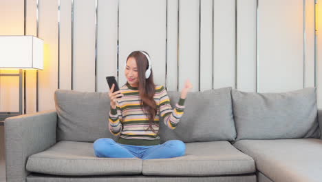 전화 및 헤드폰 음악을 듣고 춤을 소파에 소녀