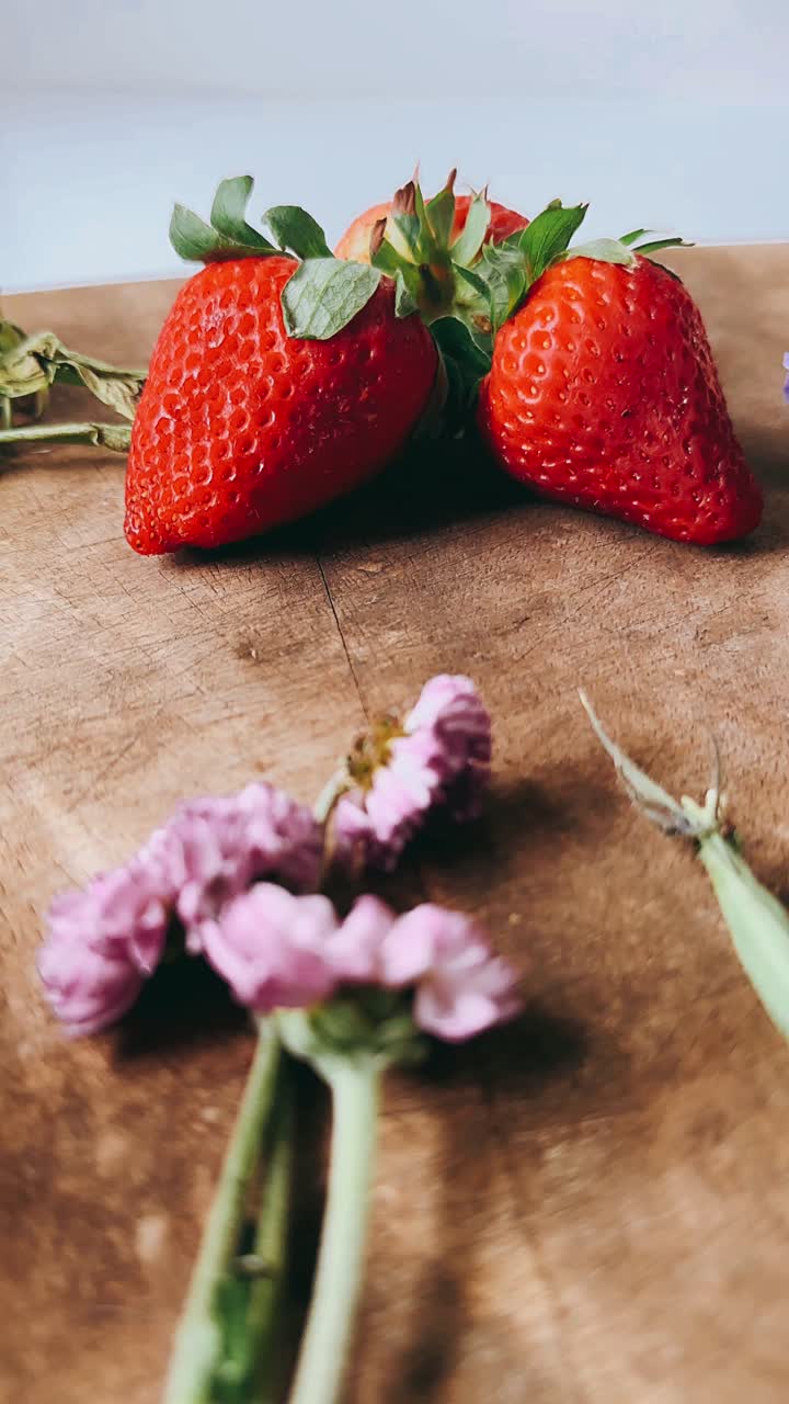 fresas y flores en una tabla de madera