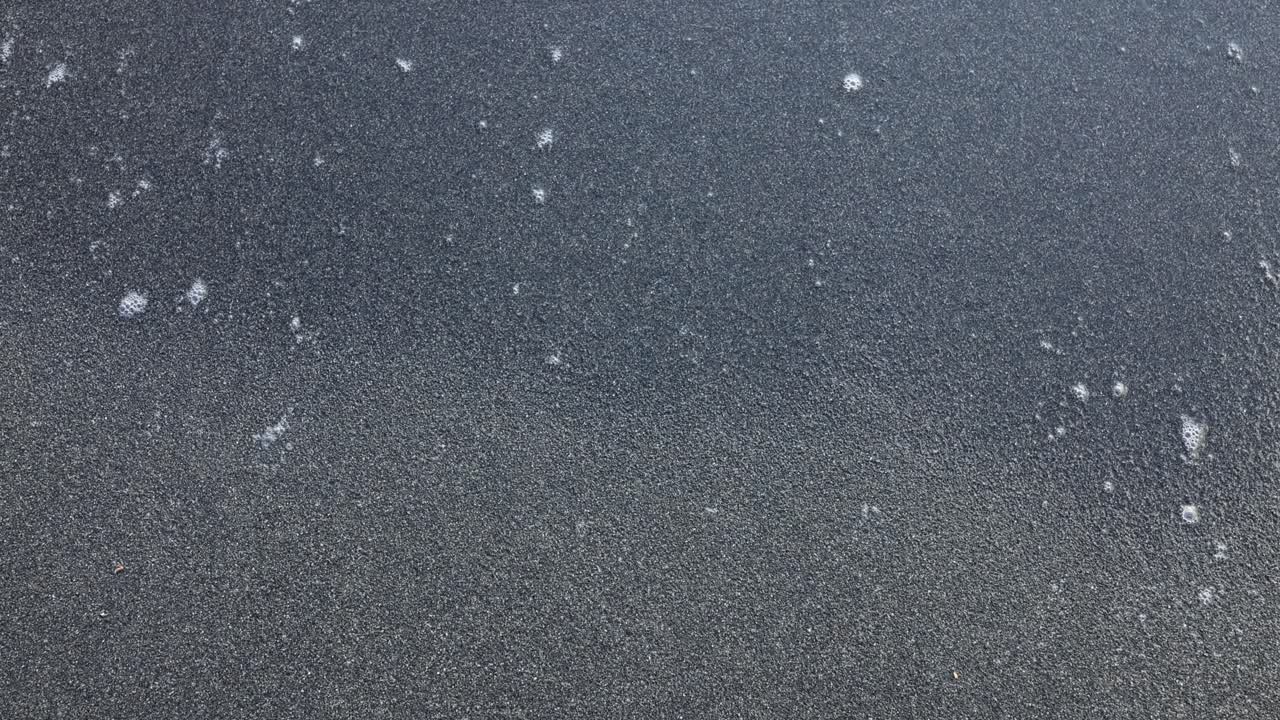 Seafoam Patterns on Dark Sand Beach