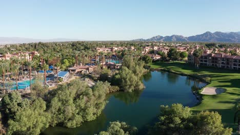 toma aérea panorámica baja de un exuberante campo de golf en un resort en palm desert, california