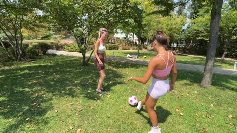 Two women playing soccer in the park