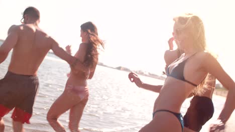 young hipster friends in swimsuits running into the sea