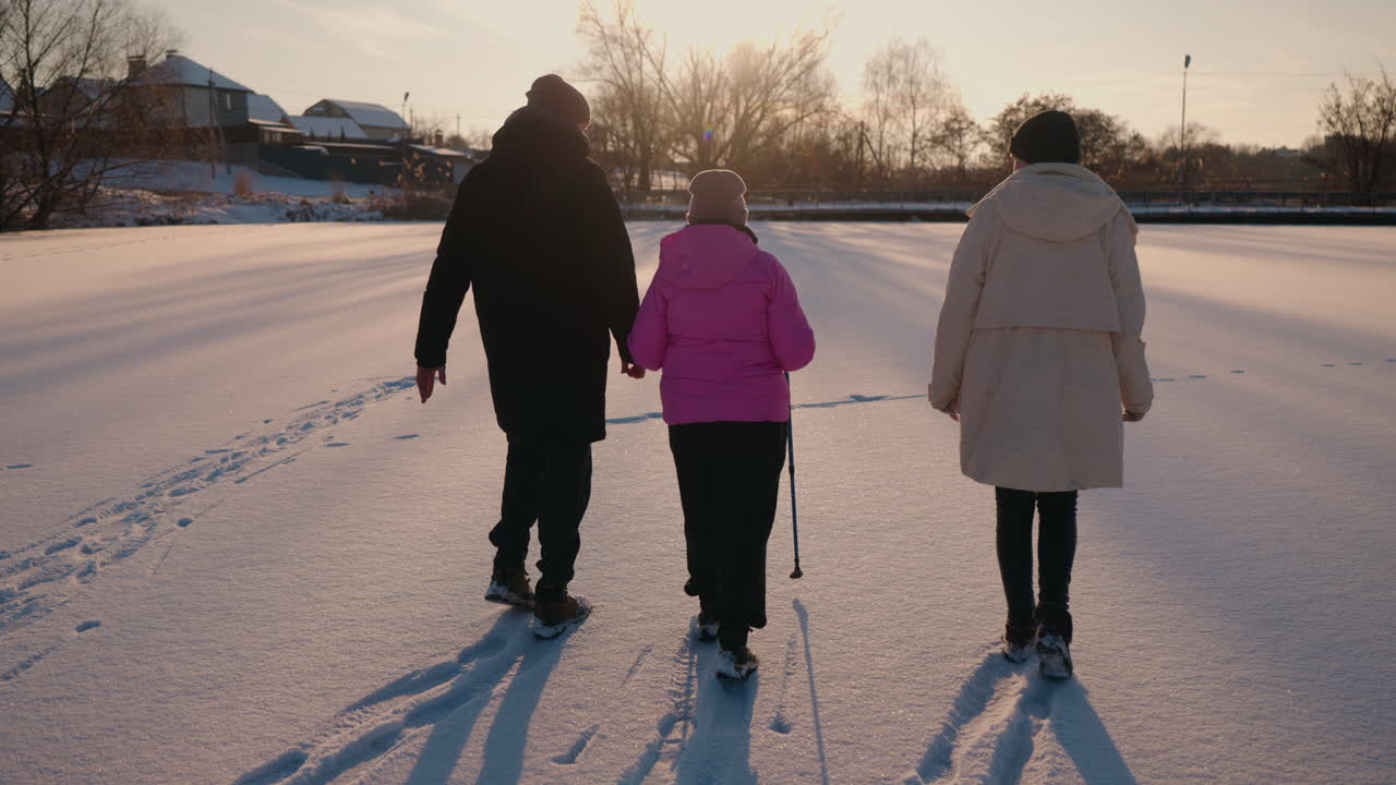 Three people walking on a frozen lake at sunset