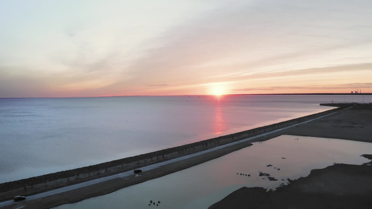 해안, 도로 및 운전 자동차와 함께 바다 위의 아름다운 일몰