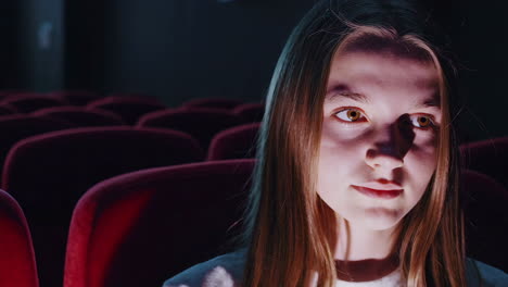 teenage girl watching a movie in a theater