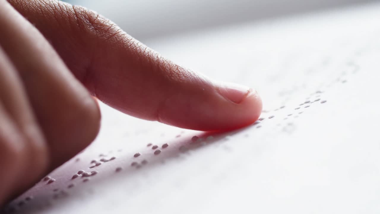 Schoolkid reading a braille book in classroom at school