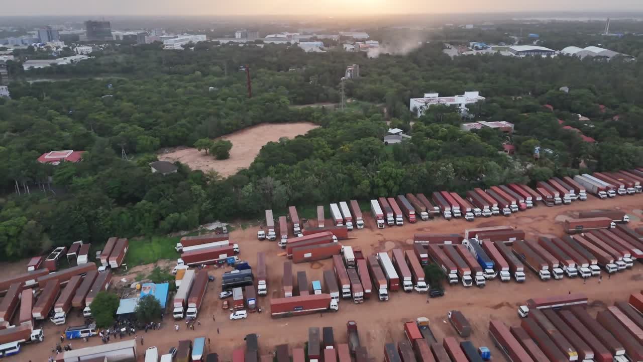 As evening settles in Chennai, this aerial video reveals a massive logistics depot where hundreds of commercial trucks and lorries are parked for the night. The vast yard, surrounded by lush greenery