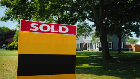 A-Plate-With-The-Words-Sold-In-The-Background-A-Typical-American-House-With-The-Usa-Flag