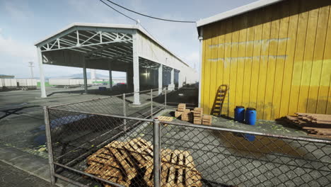 a run down warehouse with a chain link fence and piles of wood pallets