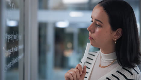 woman thinking and planning with a marker on a glass board
