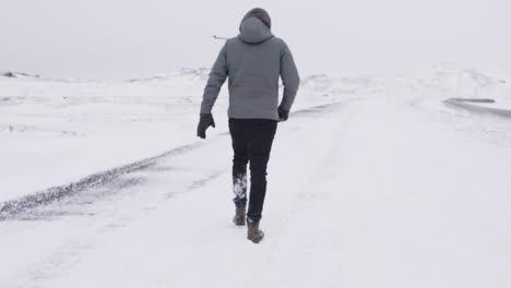 young male traveler walking through blizzard in slow motion