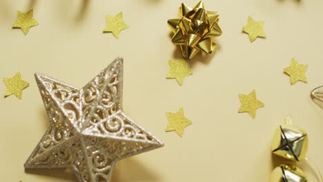 Video-of-gold-christmas-decorations-with-stars-on-yellow-background