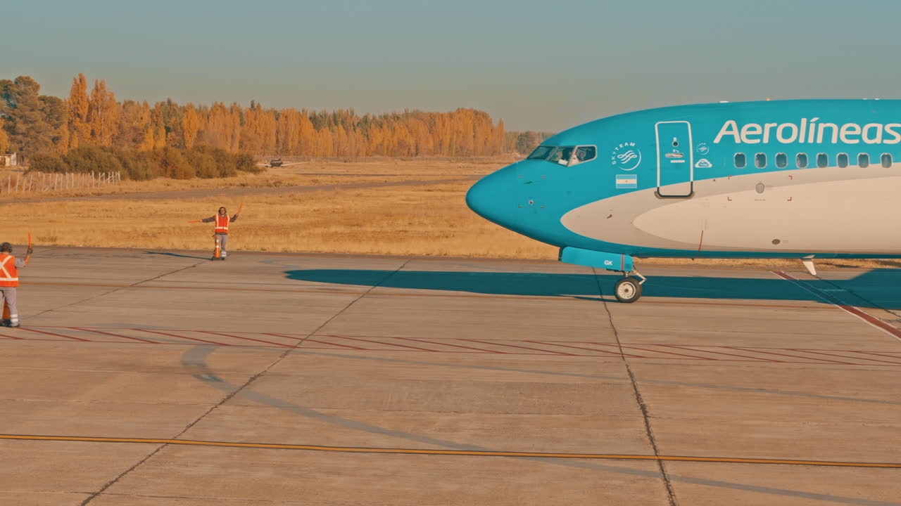 Bakkemannskap som veileder et Aerolíneas Argentinas-fly på rullebanen