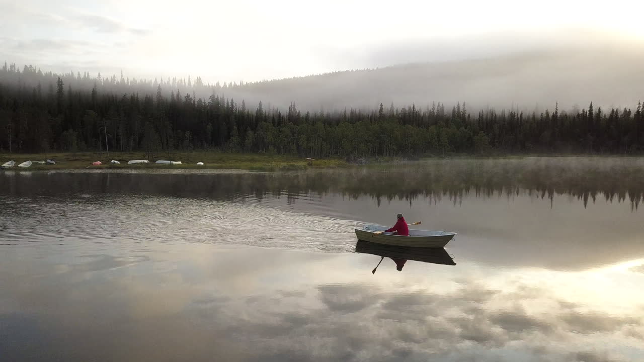 Small rowing boat on a foggy lake during a sunrise