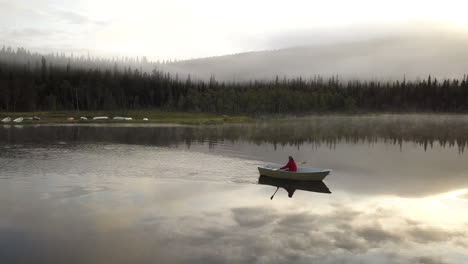pequeño bote de remos en un lago brumoso durante un amanecer