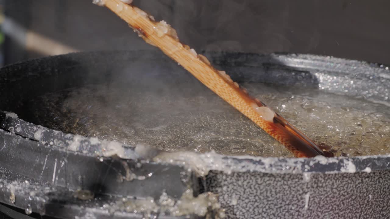 Making fruits in boiling caramel close-up. Chinese winter sweet dessert Tanghulu street food.Berries, grapes, tangerine and others fruit caramelized in sugar. Asian street market with traditional food.. High quality 4k footage