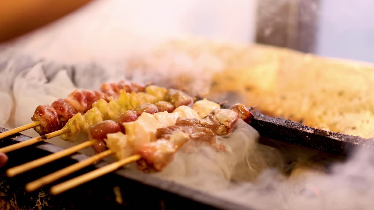 A detailed view of skewered meat cooking over a smoky grill, highlighting the grilling process and smoke.