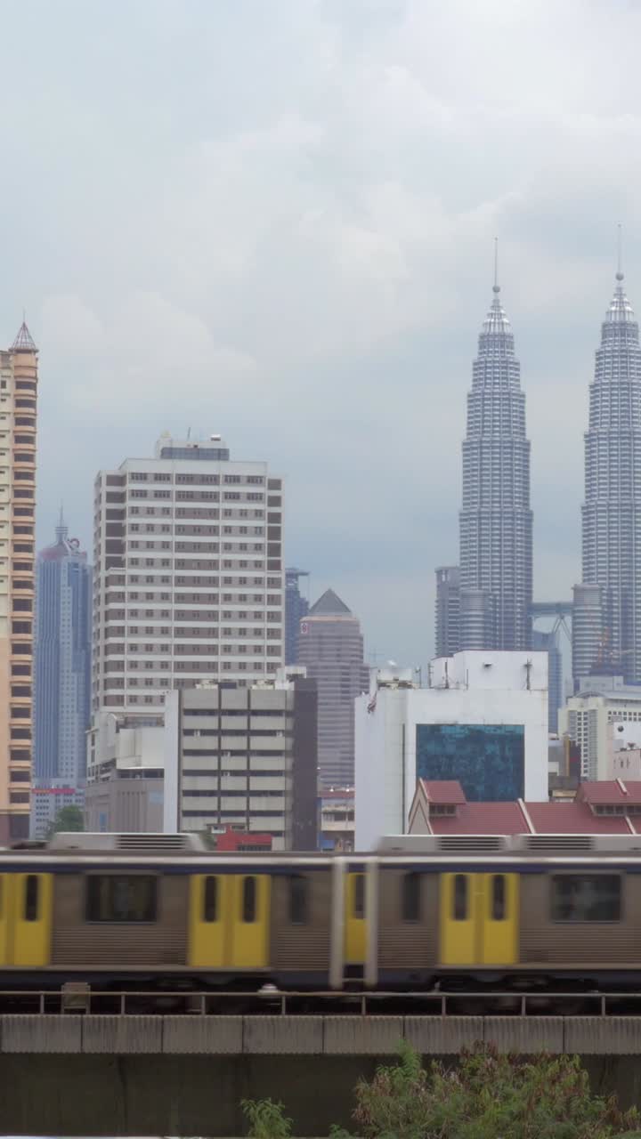 Treno che passa accanto allo skyline di Kuala Lumpur con le Petronas Twin Towers