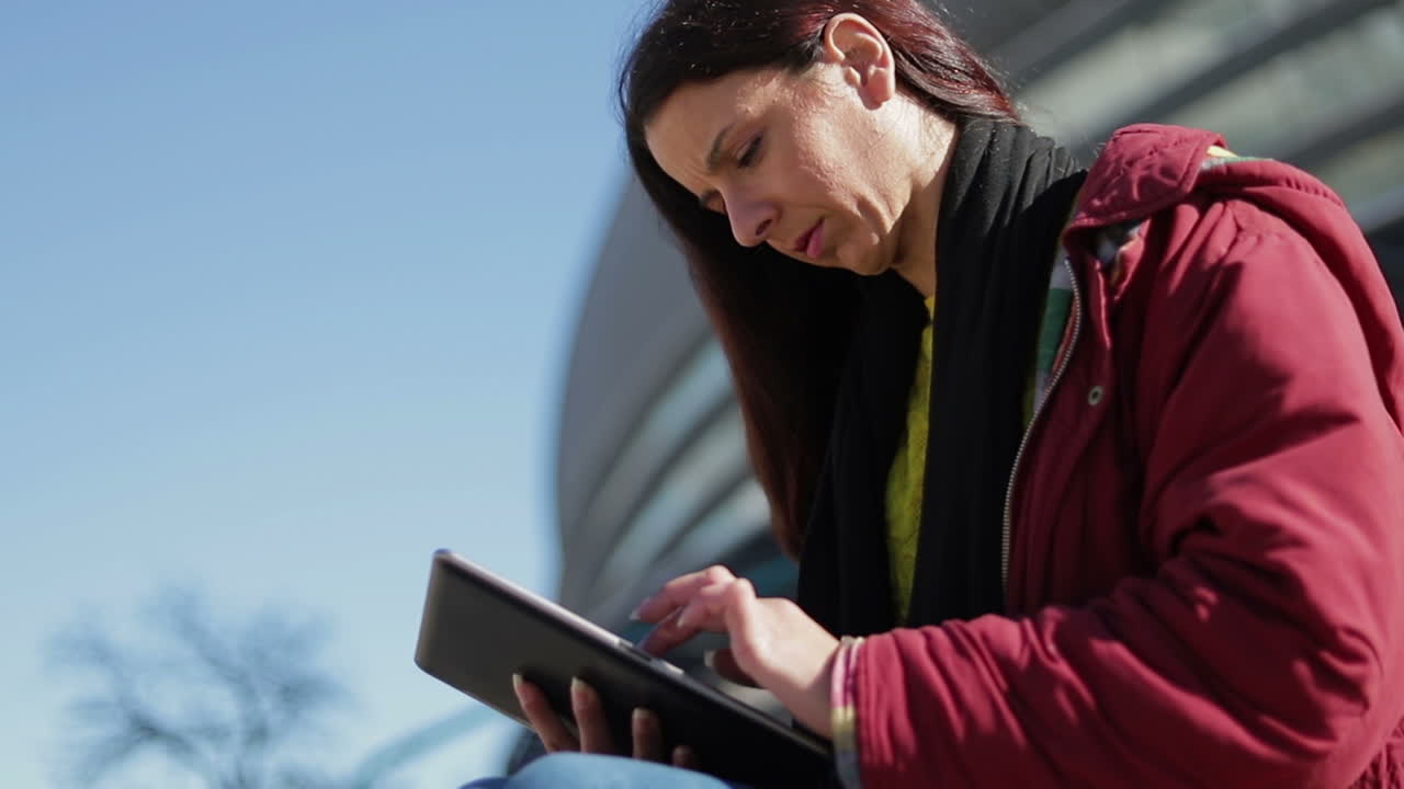 disparo en cámara lenta de una mujer seria usando una tableta al aire libre