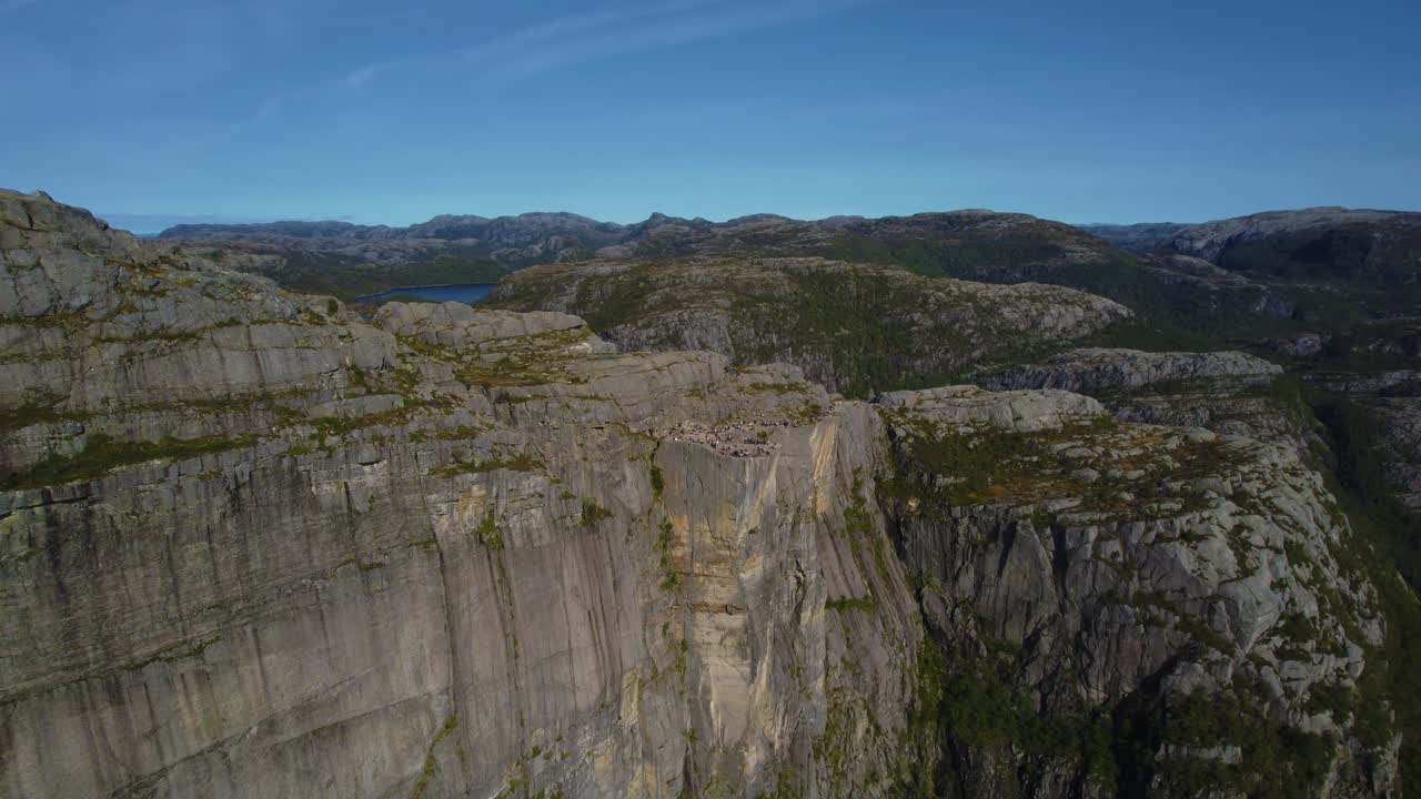 Panoramic aerial footage of Preikestolen rock, Norway. Mountain tops and fjord vista under blue skies