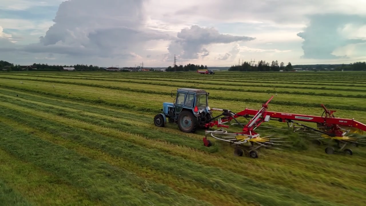 Nærbillede fra drone, der følger en traktor, der trækker en høvender
