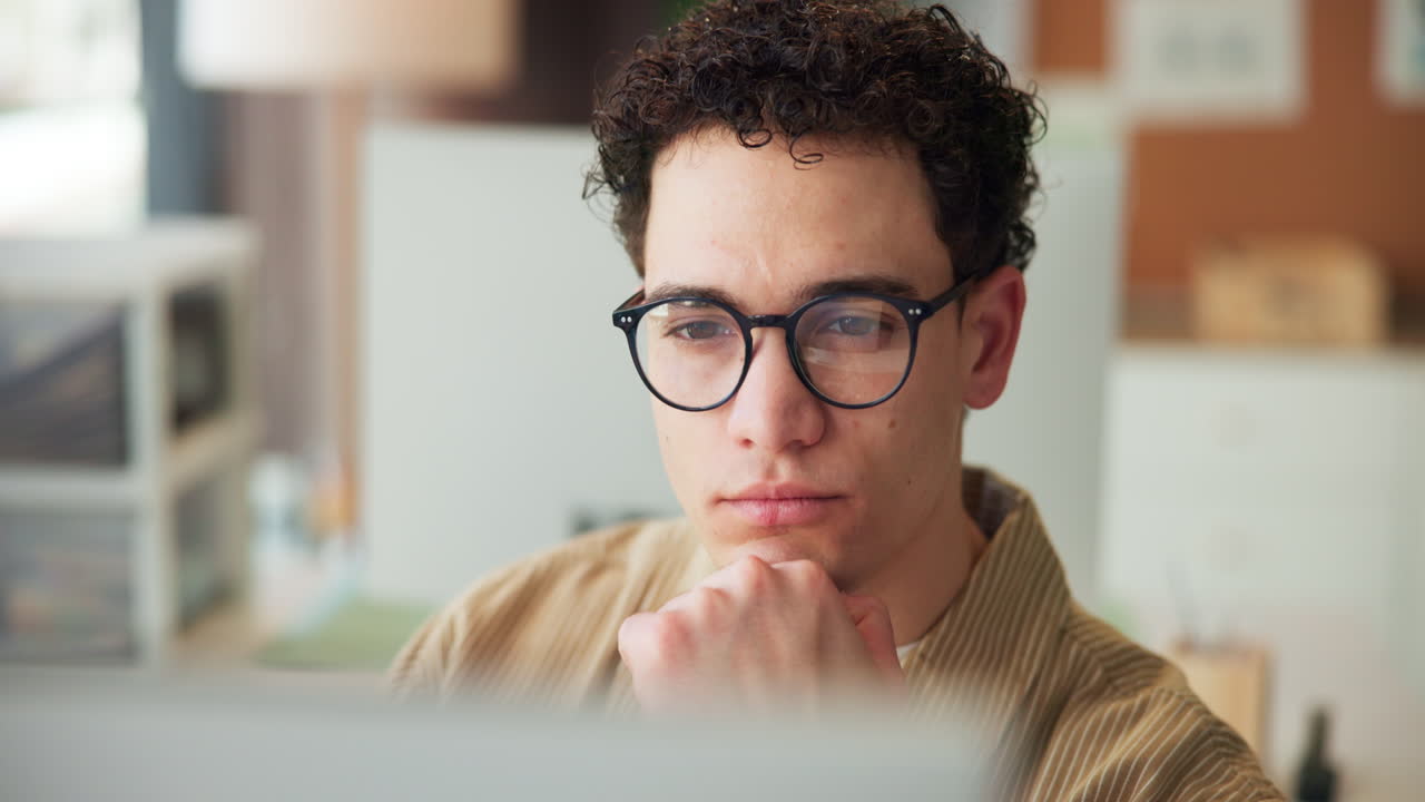 Young Man with Glasses Concentrating While Working on Computer