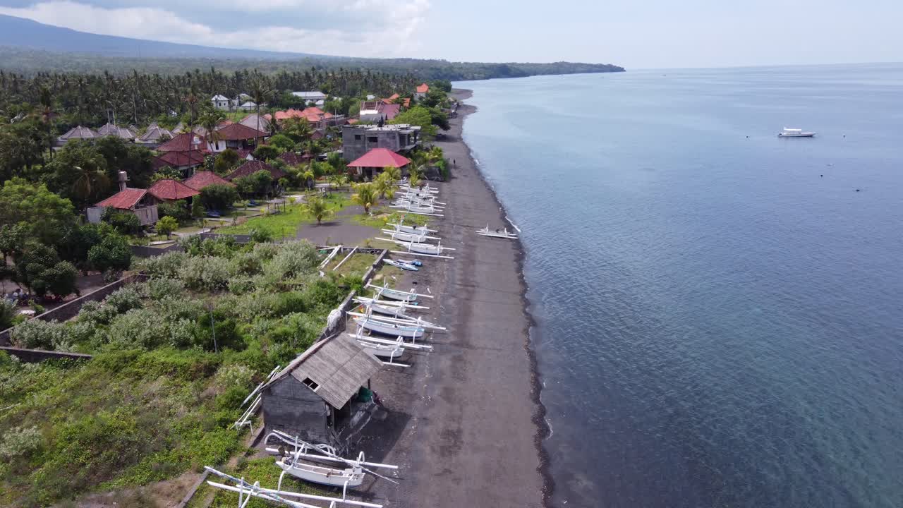 Unique volcanic black sand beach with traditional jukungs of Amed Bali. Drone