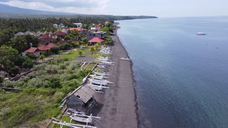 unique volcanic black sand beach with traditional jukungs of amed bali. drone
