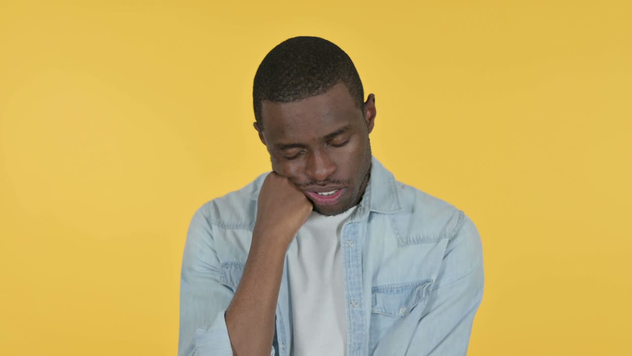 Sleepy Young African Man taking Nap, Yellow Background
